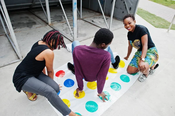 Grupp av tre afroamerikanska vänner spela Twister spel utomhu — Stockfoto