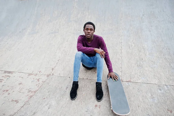 スケートボアとポーズをとった紫色のジャンパーを身にまとった若いアフリカ系アメリカ人男性 — ストック写真
