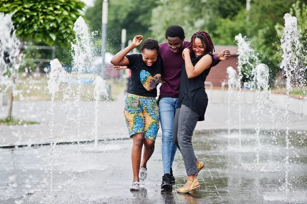 Three african american friends walking on fountains. Having fun