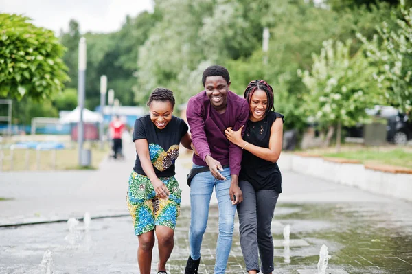 Tres amigos afroamericanos caminando sobre fuentes. Divertirse — Foto de Stock