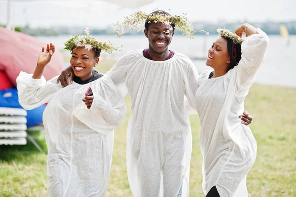 Tres amigos afroamericanos en capas blancas y guirnaldas teniendo — Foto de Stock