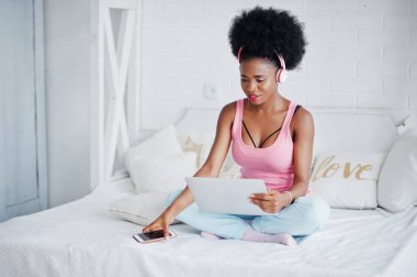Genç afro-amerikan kadın kucağında çalışırken yatakta oturan