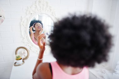 Genç afro-amerikan kadın aynaya bakarak ve mu dinlemek