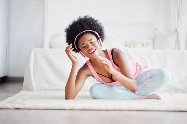 Ung afrikansk amerikansk kvinna i rosa linne lyssna musik på örat — Stockfoto