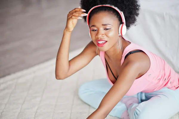 Ung afrikansk amerikansk kvinna i rosa linne lyssna musik på örat — Stockfoto