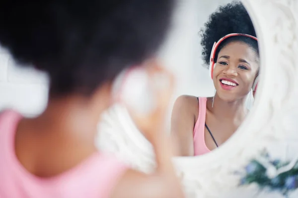 Young african american woman looking at the mirror and listen mu