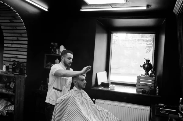 Young bearded man getting haircut by hairdresser while sitting i — Stock Photo, Image