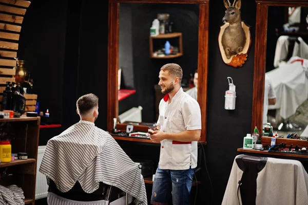 Jovem barbudo homem chegando corte de cabelo por cabeleireiro enquanto sentado eu — Fotografia de Stock