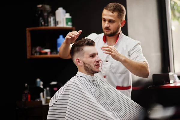 Jovem barbudo homem chegando corte de cabelo por cabeleireiro enquanto sentado eu — Fotografia de Stock