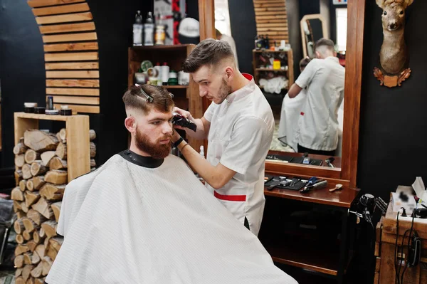 Young bearded man getting haircut by hairdresser while sitting i — Stock Photo, Image