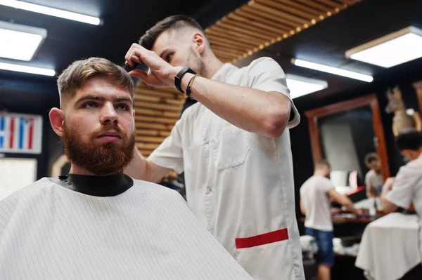 Молодий бородатий чоловік отримує зачіску від перукаря, сидячи я — стокове фото