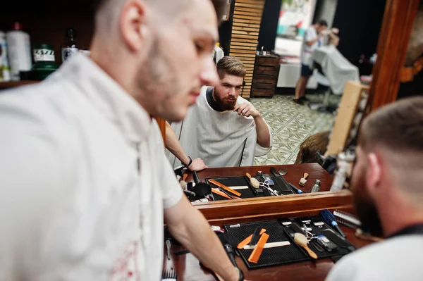 Young bearded man getting haircut by hairdresser while sitting i — Stock Photo, Image