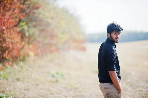 Indisk man på svart skjorta och beige byxor poserade på fältet mot — Stockfoto