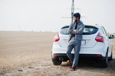 Rahat giyim Hintli adam beyaz araba yakınında poz verdi.