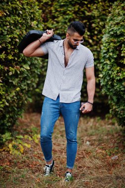 Modaya uygun uzun sakallı adam gömlek, kot pantolon ve güneş gözlüğü giyiyor.