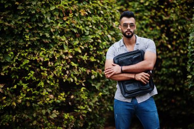 Modaya uygun uzun sakallı adam gömlek, kot pantolon ve güneş gözlüğü giyiyor.