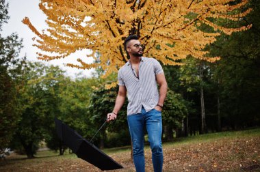 Modaya uygun uzun sakallı adam gömlek, kot pantolon ve güneş gözlüğü giyiyor.