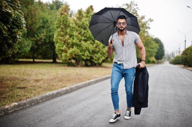 Modaya uygun uzun sakallı adam gömlek, kot pantolon ve güneş gözlüğü giyiyor.