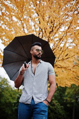 Modaya uygun uzun sakallı adam gömlek, kot pantolon ve güneş gözlüğü giyiyor.