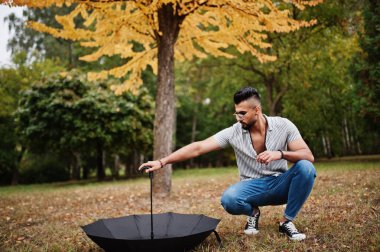 Modaya uygun uzun sakallı adam gömlek, kot pantolon ve güneş gözlüğü giyiyor.