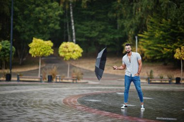 Modaya uygun uzun sakallı adam gömlek, kot pantolon ve güneş gözlüğü giyiyor.