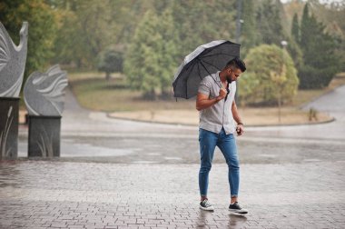 Modaya uygun uzun sakallı adam gömlek, kot pantolon ve güneş gözlüğü giyiyor.
