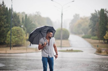 Modaya uygun uzun sakallı adam gömlek, kot pantolon ve güneş gözlüğü giyiyor.