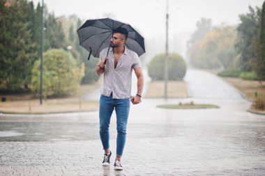 Modaya uygun uzun sakallı adam gömlek, kot pantolon ve güneş gözlüğü giyiyor.