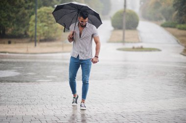 Modaya uygun uzun sakallı adam gömlek, kot pantolon ve güneş gözlüğü giyiyor.