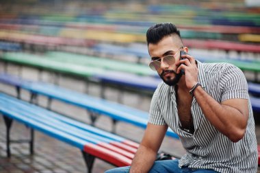 Modaya uygun uzun sakallı adam gömlek, kot pantolon ve güneş gözlüğü giyiyor.