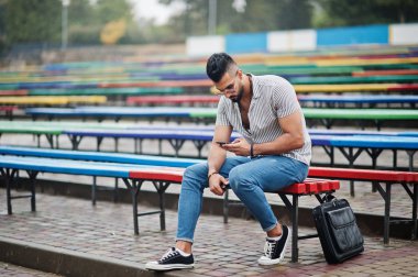 Modaya uygun uzun sakallı adam gömlek, kot pantolon ve güneş gözlüğü giyiyor.