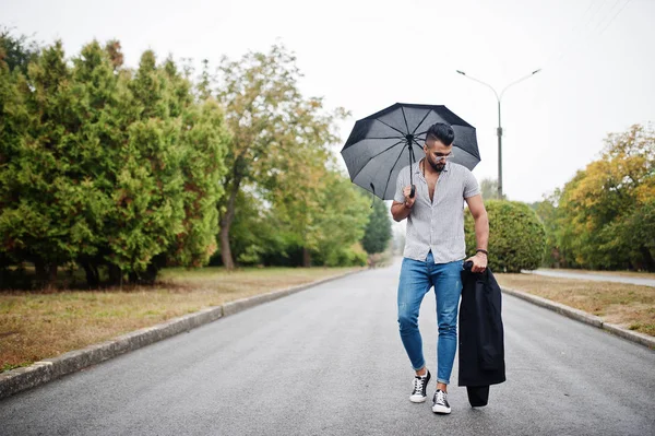 Modaya uygun uzun sakallı adam gömlek, kot pantolon ve güneş gözlüğü giyiyor.