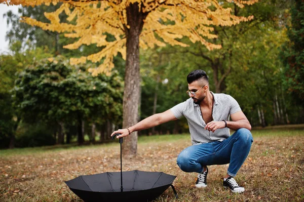 Modaya uygun uzun sakallı adam gömlek, kot pantolon ve güneş gözlüğü giyiyor.