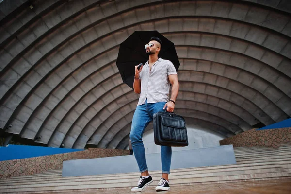 Modaya uygun uzun sakallı adam gömlek, kot pantolon ve güneş gözlüğü giyiyor.