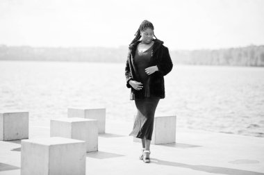 Afro-amerikan esmer tenli artı boyut modeli mavi bir şey poz vermiş.