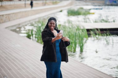 Afro-amerikan esmer tenli artı boyut modeli mavi bir şey poz vermiş.