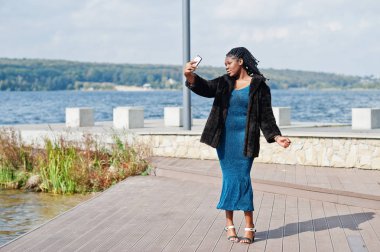 Afro-amerikan esmer tenli artı boyut modeli mavi bir şey poz vermiş.