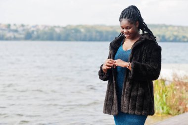 Afro-amerikan esmer tenli artı boyut modeli mavi bir şey poz vermiş.