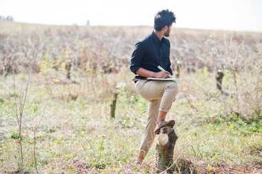 Kesilen ağacı incelemek için panosu olan Güney Asyalı zirai çiftçi