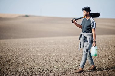 Güney Asyalı tarımcı çiftçi elinde kürekle kara toprağı inceliyor..