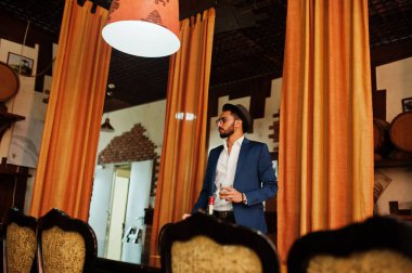 Bir bardak viski ve puro ile yakışıklı, iyi giyimli bir Arap.