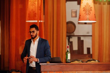 Bir bardak viski ve puro ile yakışıklı, iyi giyimli bir Arap.