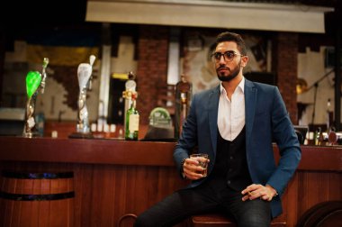 Bir bardak viski ve puro ile yakışıklı, iyi giyimli bir Arap.