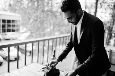 Yakışıklı, iyi giyimli bir Arap bar balkonunda puro içiyor..