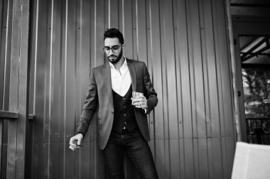 Yakışıklı, iyi giyimli Arap adam, bir bardak beyaz şarapla puro içiyor.