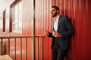 Yakışıklı, iyi giyimli Arap adam, bir bardak beyaz şarapla puro içiyor.