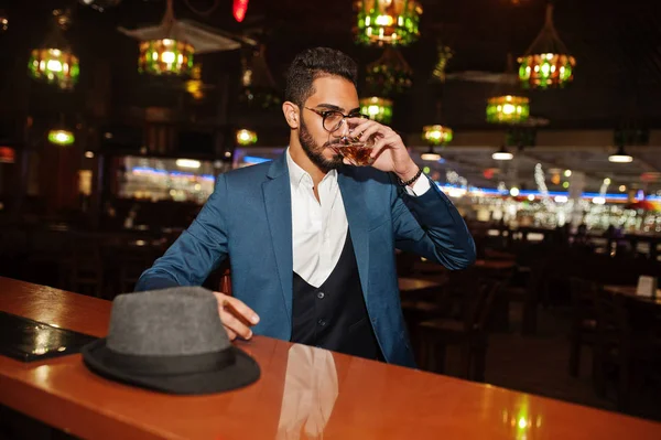 Handsome well-dressed arabian man with glass of whiskey and ciga