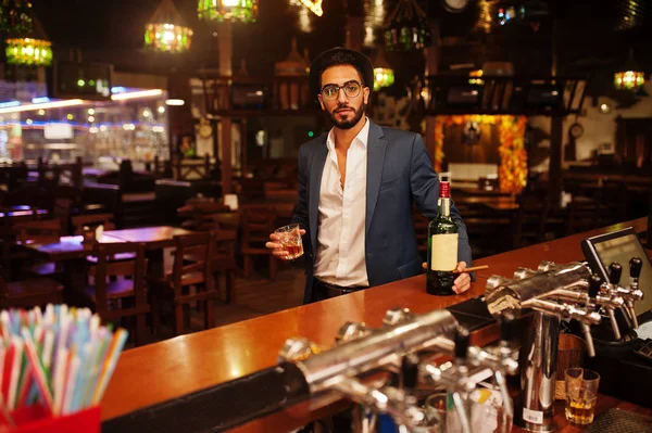 Handsome well-dressed arabian man with glass of whiskey and ciga