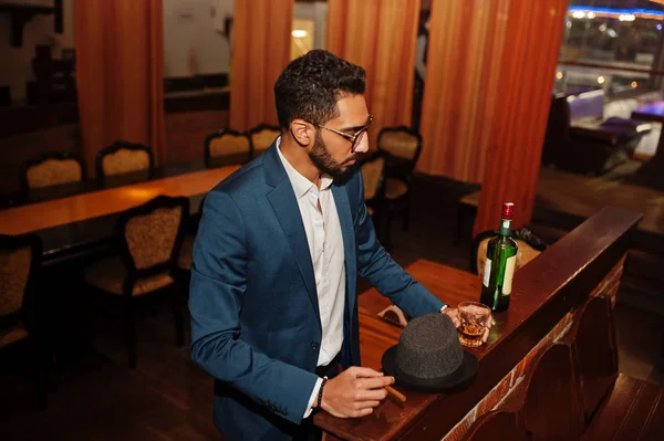 Handsome well-dressed arabian man with glass of whiskey and ciga