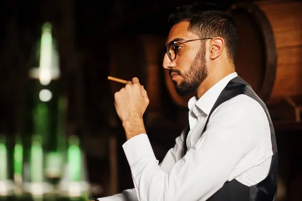 Handsome well-dressed arabian man with glass of whiskey and ciga